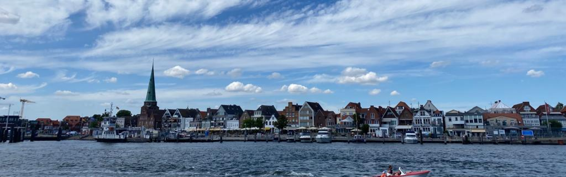 Trave, Wolken und Travemünde mit St. Lorenz im Hintergrund